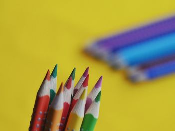 Close-up of colored pencils against yellow background