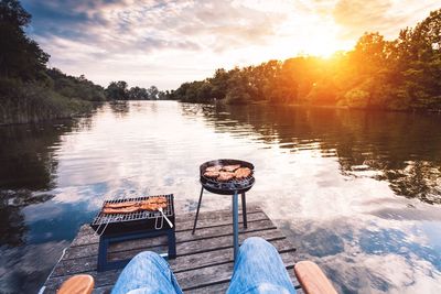 Reflection of man in lake against sky during sunset