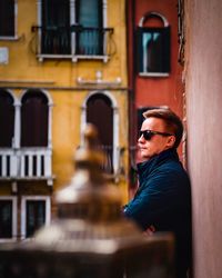 Portrait of young man standing against building