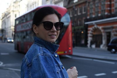 Portrait of smiling woman on road by bus in city