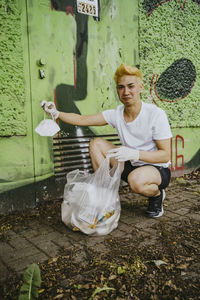 Portrait of male volunteer showing protective face mask while cleaning plastic