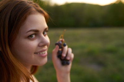 Portrait of young woman holding camera on field