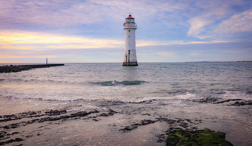 Lighthouse by sea against sky