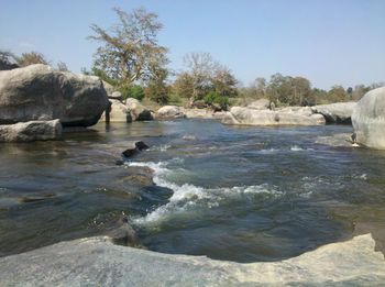 Rocks in sea against clear sky