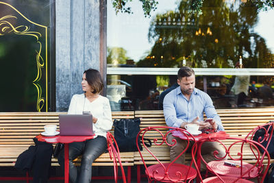 Business people using technologies at sidewalk cafe