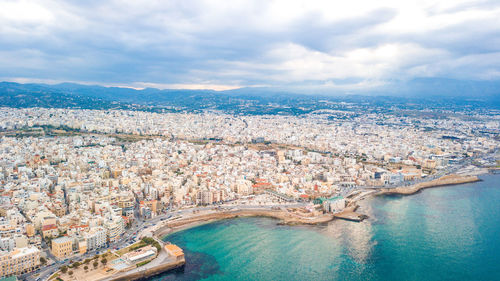 High angle view of city buildings against cloudy sky