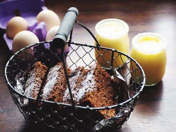 High angle view of fresh carrot cakes in metallic basket with egg crate and drink