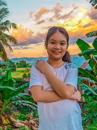 Portrait of smiling young woman standing on land against sky