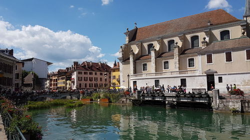 Group of people in canal by buildings in town