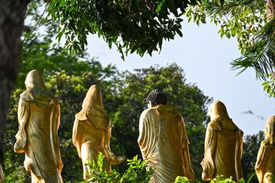 Rear view of golden buddha statue against trees