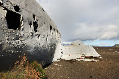 Abandoned airplane on land against sky