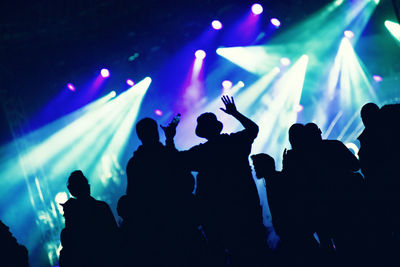 Silhouette of hands on a concert in front of bright stage lights