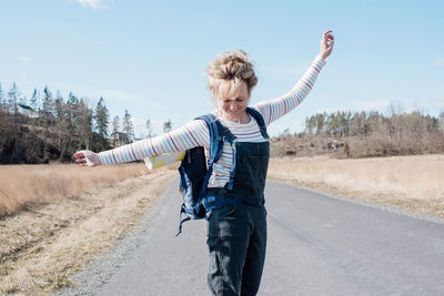 Woman enjoying skating along a country road with a yoga mat in her bag