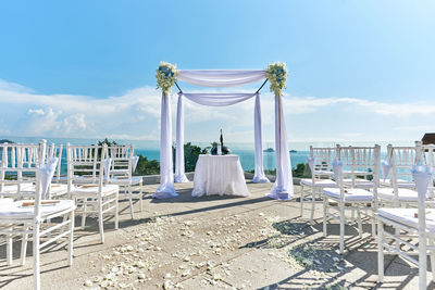 Deck chairs on beach against sky