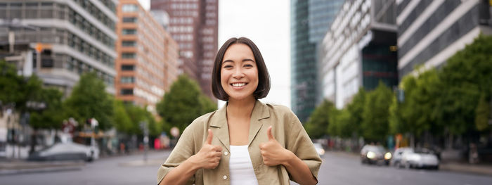 Portrait of young woman standing in city