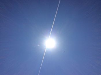 Low angle view of sun shining through clouds