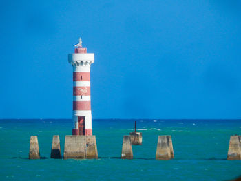 Lighthouse by sea against sky