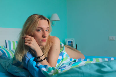 Portrait of young woman lying on bed at home
