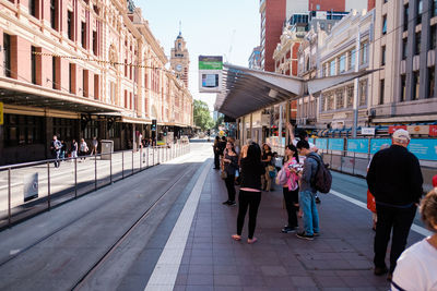 People walking on street amidst buildings in city