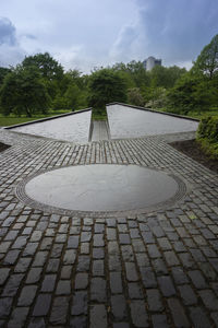 Footpath by street in city against sky