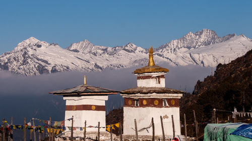 Built structure by snowcapped mountains against clear sky