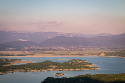 Scenic view of lake by mountains against sky during sunset