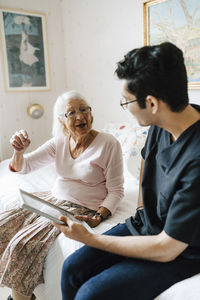 Elderly woman talking with male caregiver in bedroom