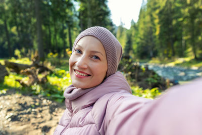 Portrait of smiling woman standing against trees