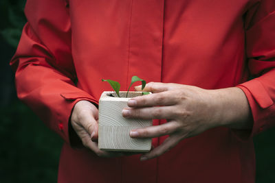 Midsection of man holding red while standing against wall