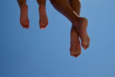 Low section of women against clear blue sky