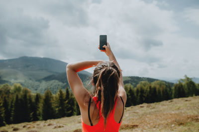 Rear view of woman using mobile phone against sky