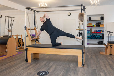 Male fitness pilates trainer shows exercises on special simulators. pilates stretch tables