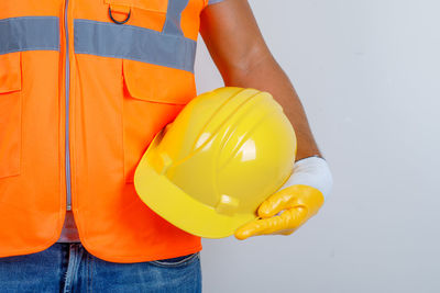 Midsection of man holding balloons against orange wall