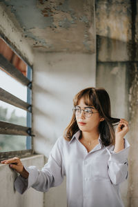 Beautiful young woman standing by window