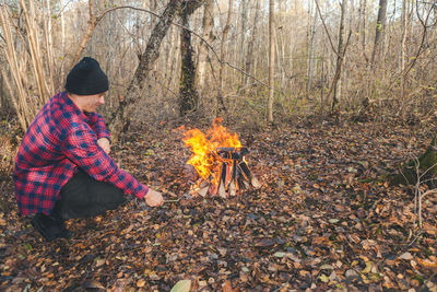 Man roasting food in campfire at forest