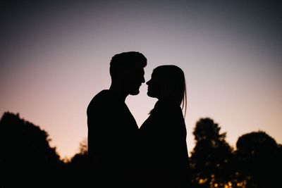 Silhouette couple standing against sky during sunset