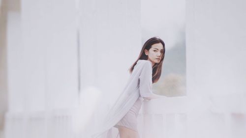 Portrait of young woman standing on bridge