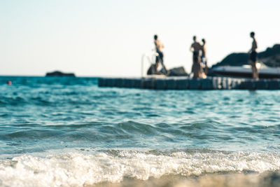 People in sea against clear sky