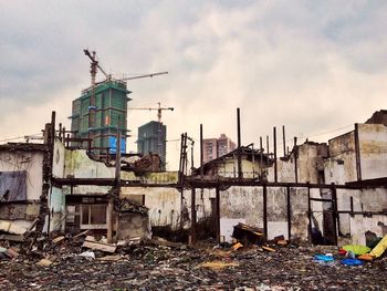 Demolished house against incomplete building in city