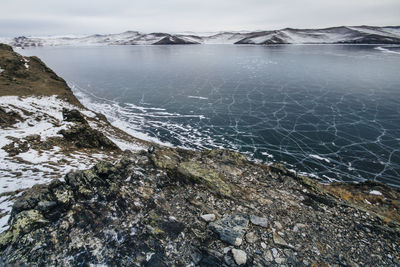 Scenic view of sea by snowcapped mountain