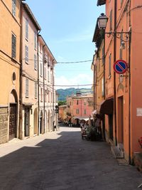 Empty road amidst buildings against sky in city