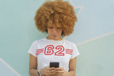 Woman with afro hair using her smartphone