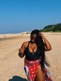 Young woman standing on beach against clear sky