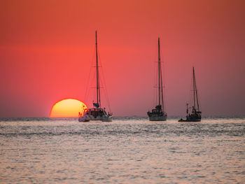 Sailboat sailing on sea against orange sky