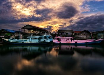 Boats moored in water against sky during sunset