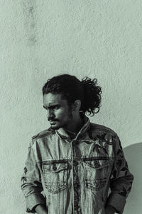 Portrait of young man looking away against wall