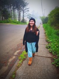 Portrait of smiling young woman standing on footpath