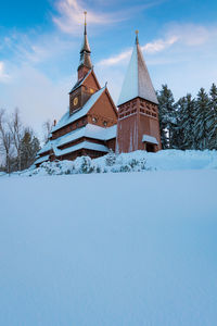 Church on field by building against sky during winter