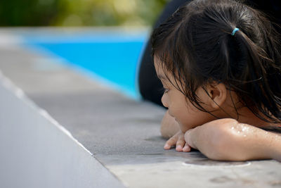 Side view of cute girl looking away while relaxing on poolside