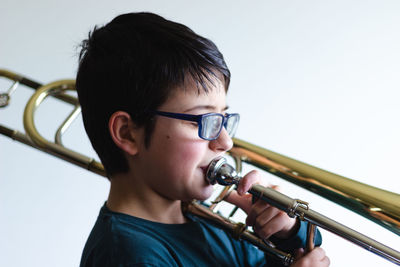 Side view of boy playing trumpet against white background